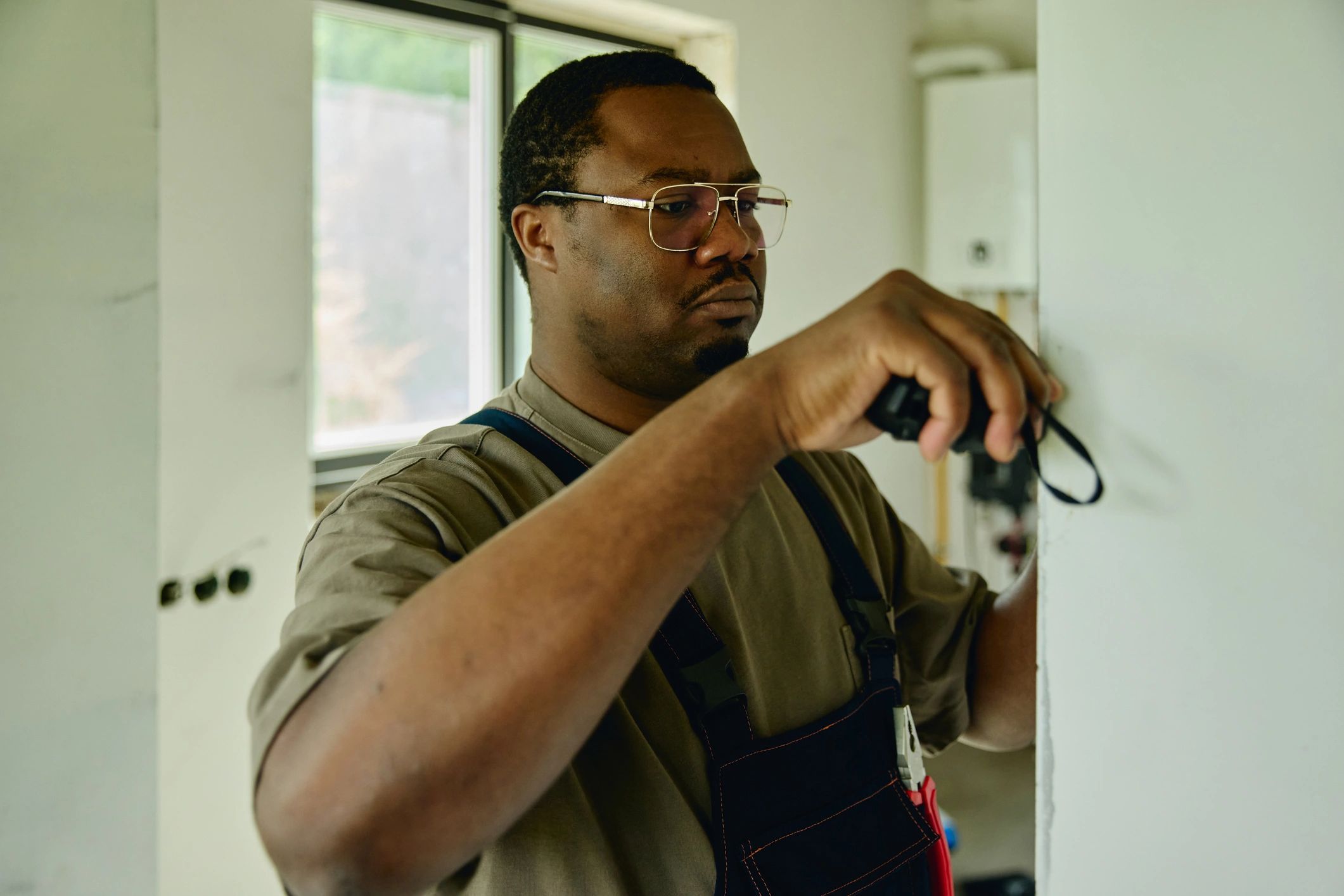Contractor measuring wall during residential renovation assessment